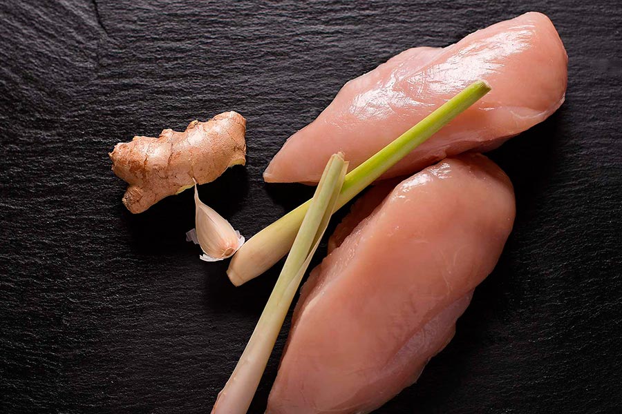Hähnchenbrust, Ingwer, Knoblauch, Zitronengras auf schwarzem Hintergrund.