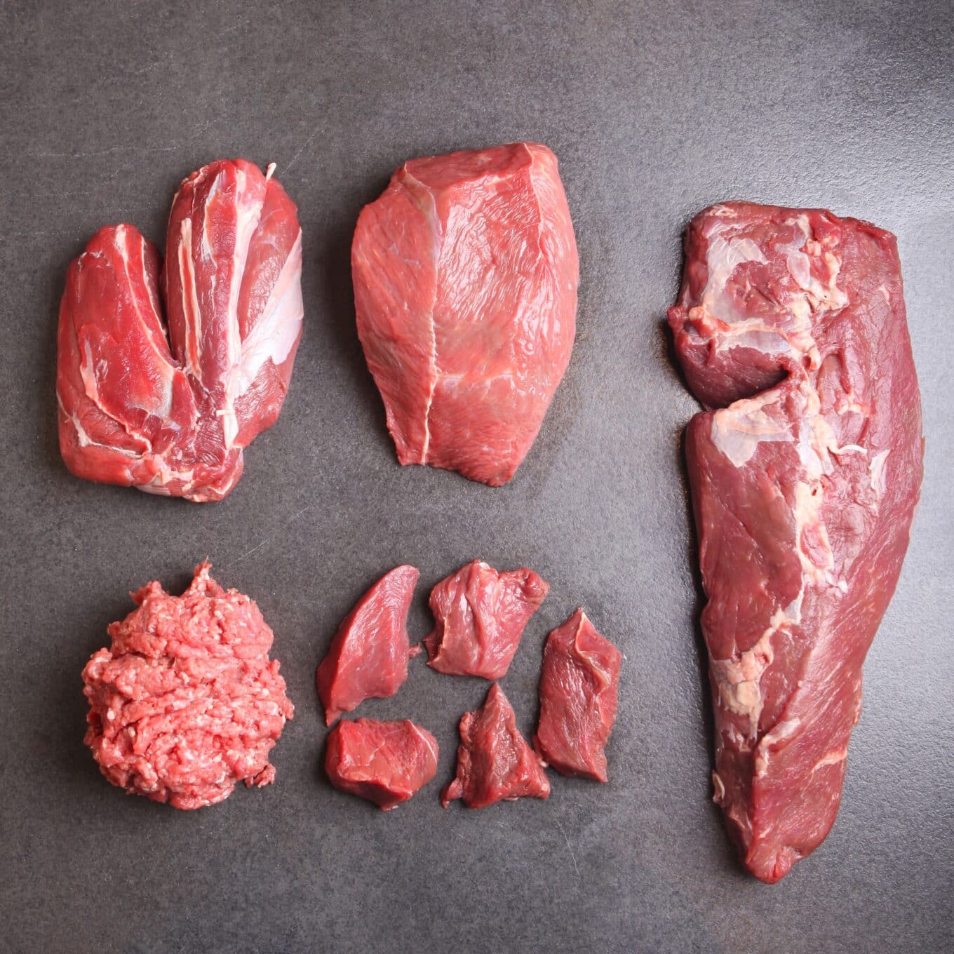 Verschiedene Stücke rohes Fleisch auf einem Tisch.