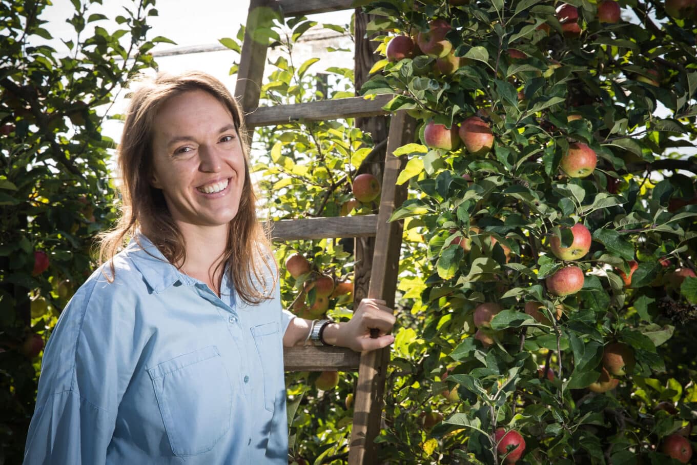 Martina Wacker lächelt im Apfelgarten neben Leiter