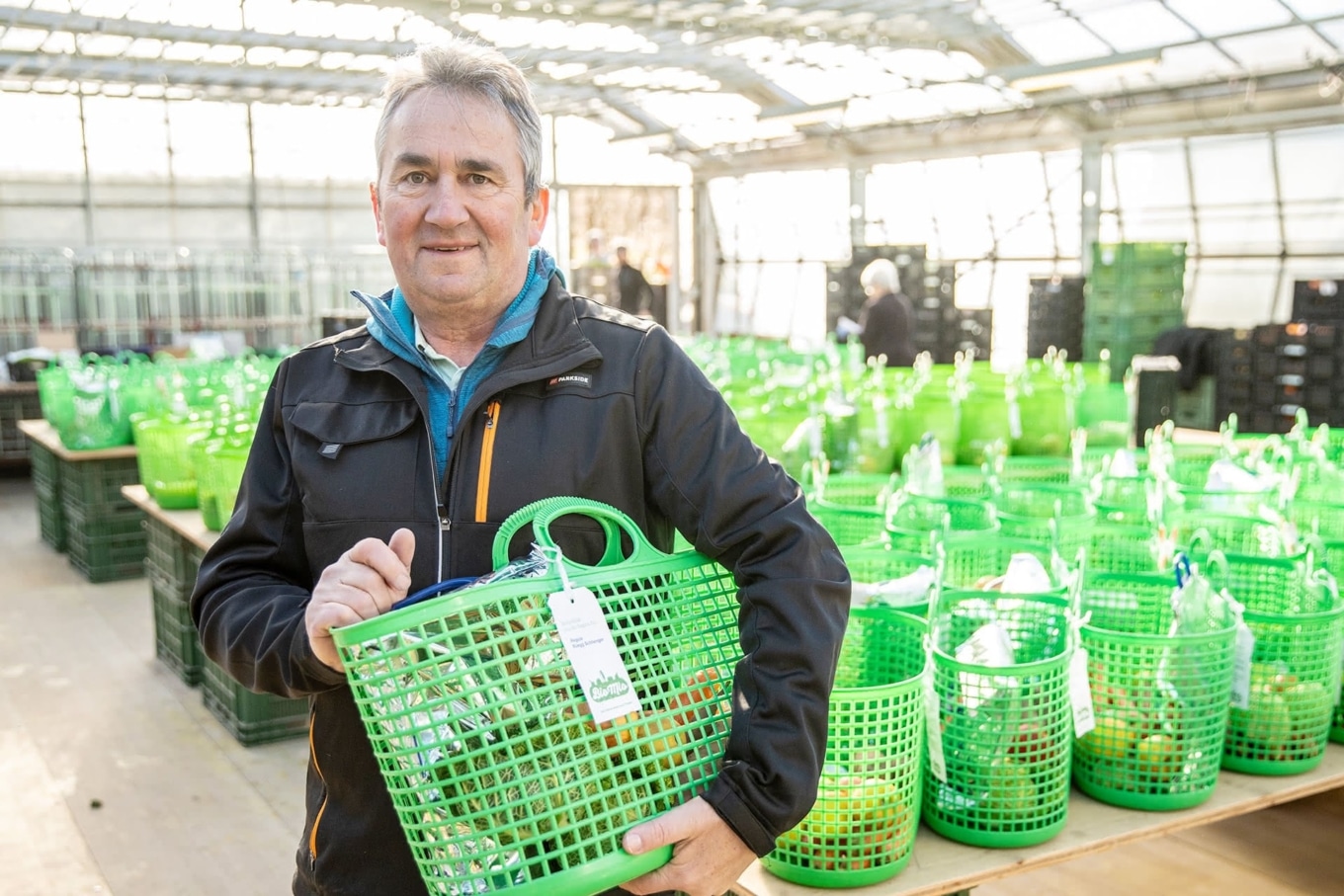 Ueli Häusler von der Stiftung zur Weid mit grünem Bio Mio Korb in Gewächshaus
