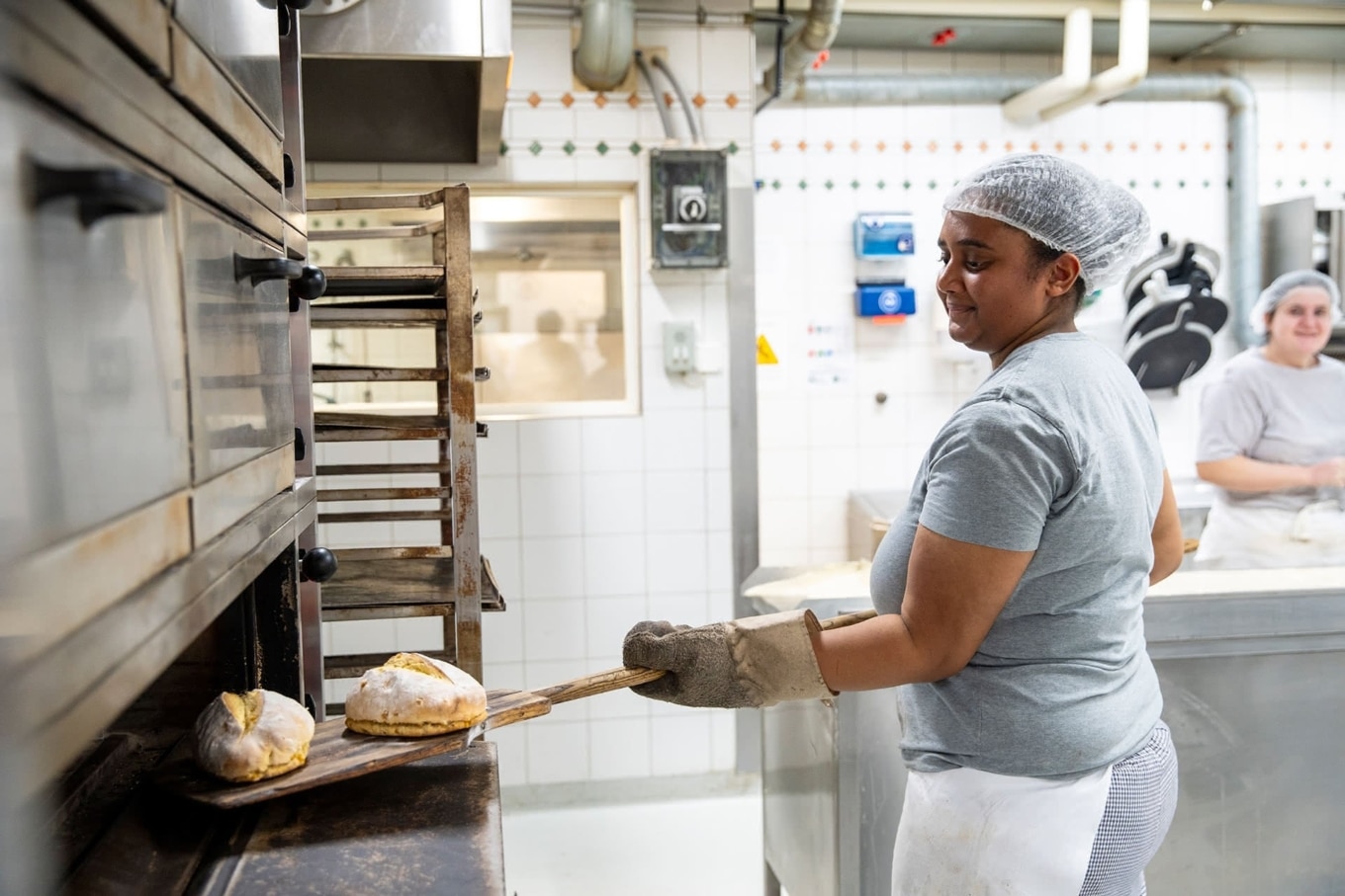 Bäckerin setzt in der Bäckerei Vier Linden Brot in Ofen ein