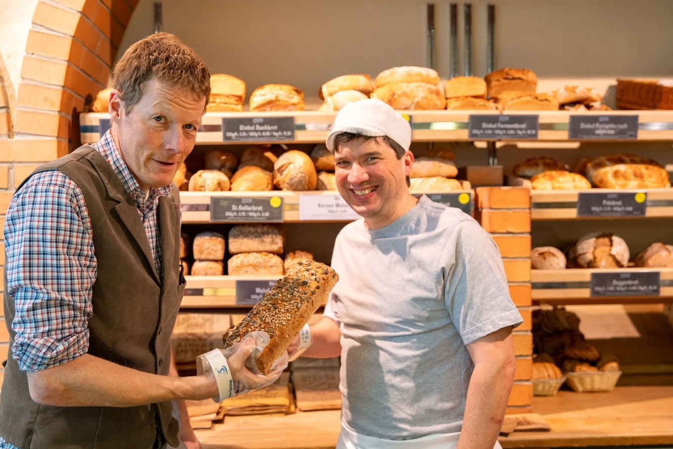 Beat Philipp (l.) und ein Bäcker präsentieren Brot in der Bäckerei Vier Linden